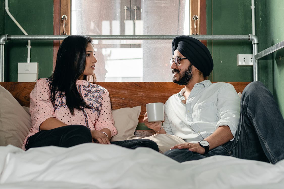 Smiling Couple Resting On Bed And Talking Free Stock Photo