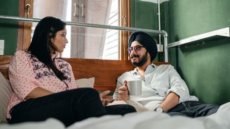 Indian couple talking in bed over coffee about trying sex toys for couples