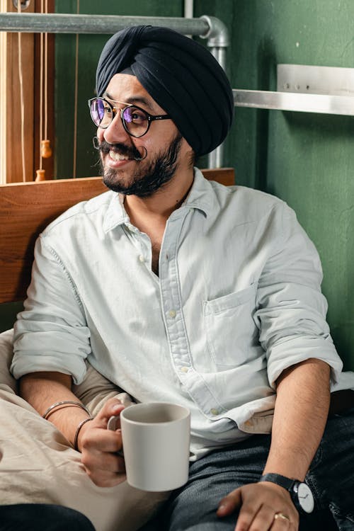 Cheerful man in turban with cup of beverage