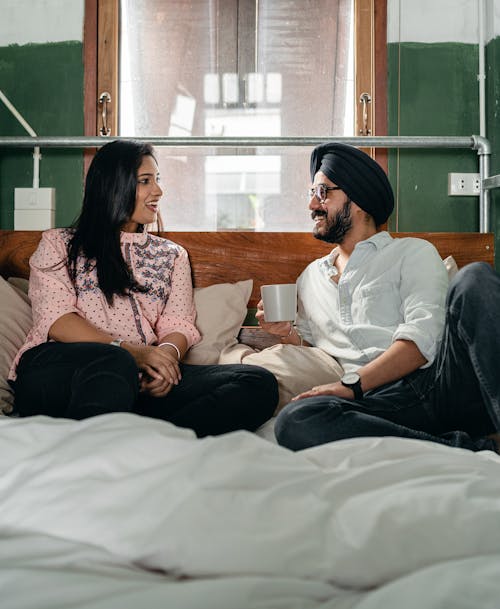 Free Happy couple chatting and lying on bed Stock Photo