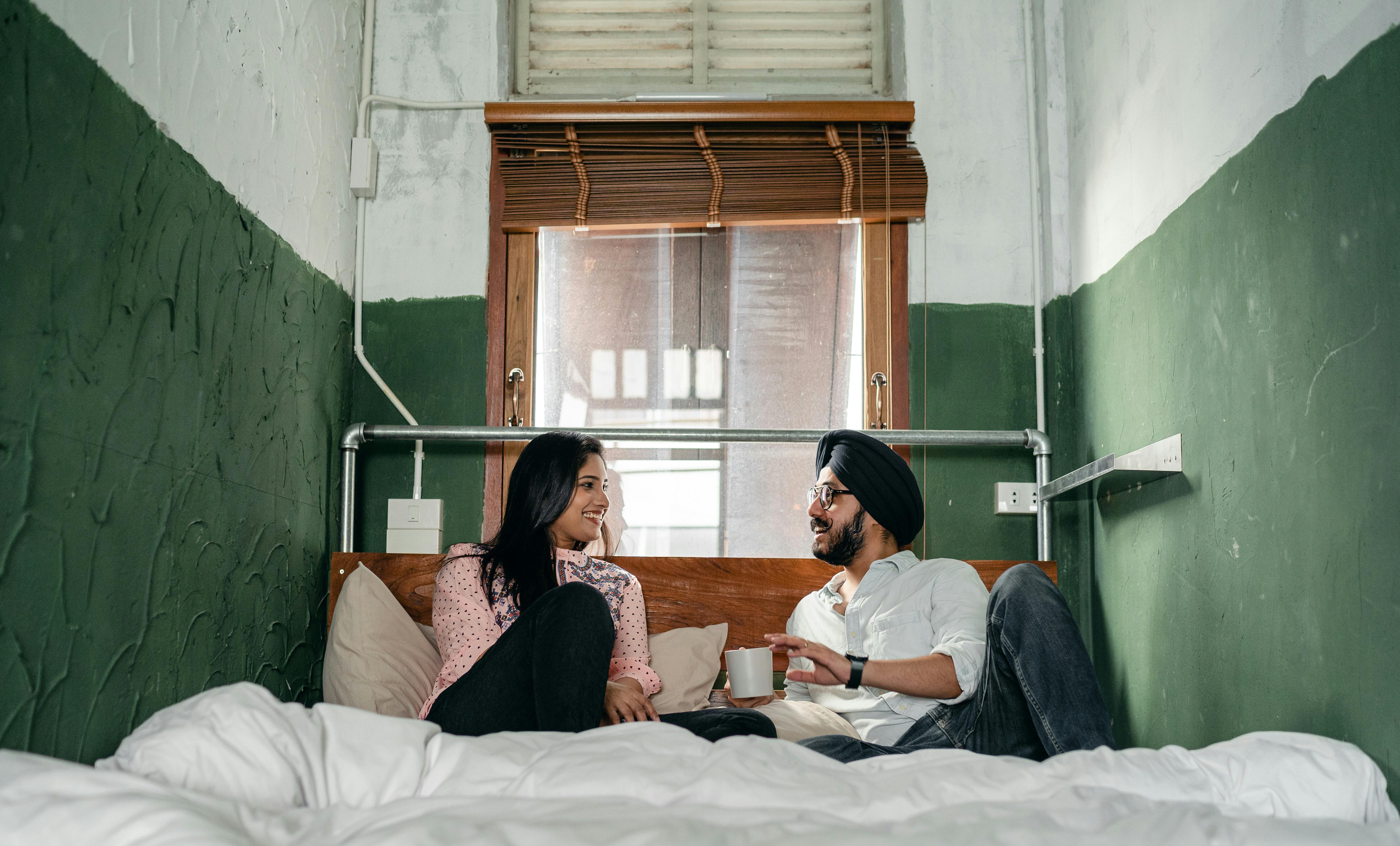 positive couple chatting on bed in narrow green room