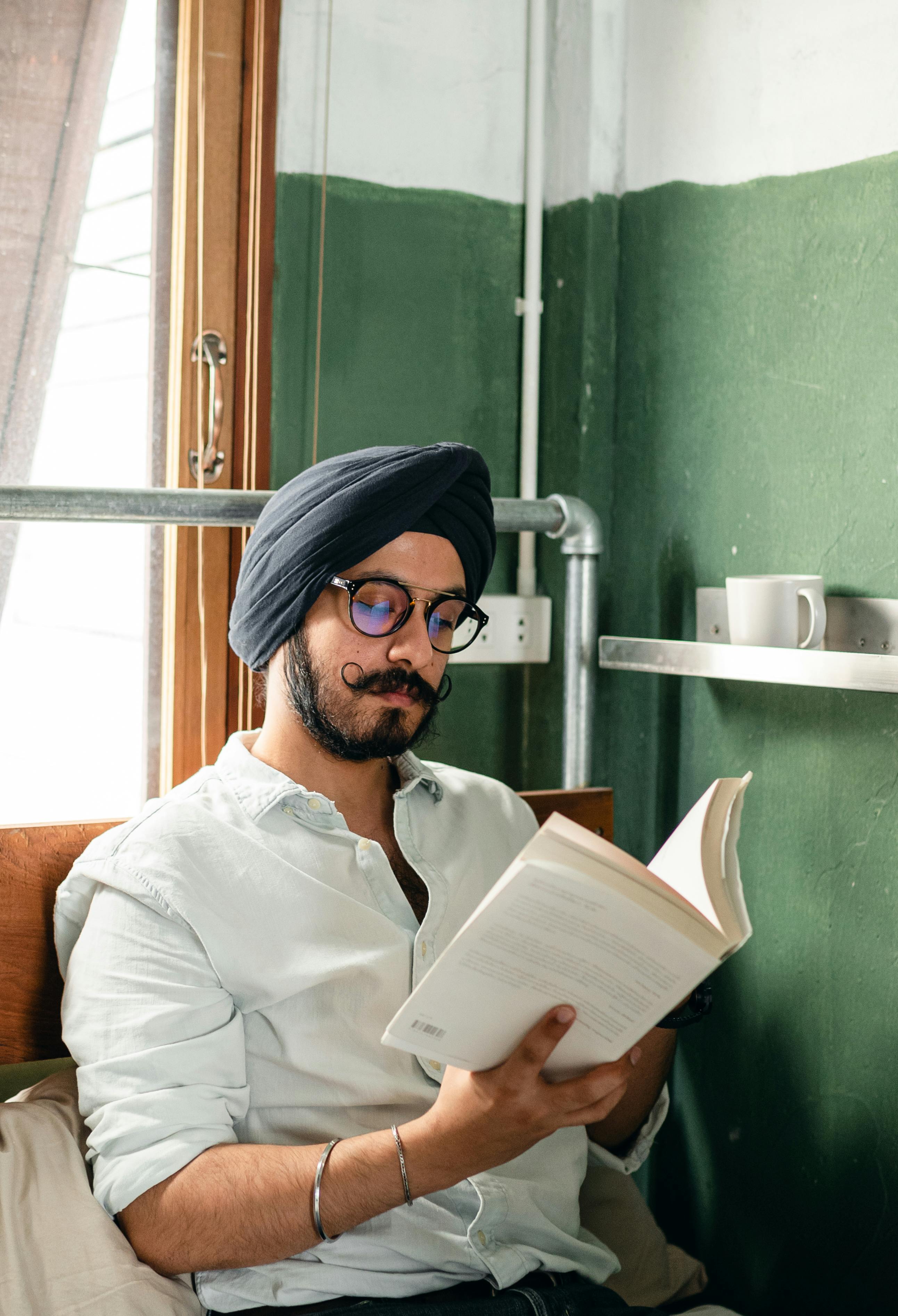 Concentrated young man in turban reading book