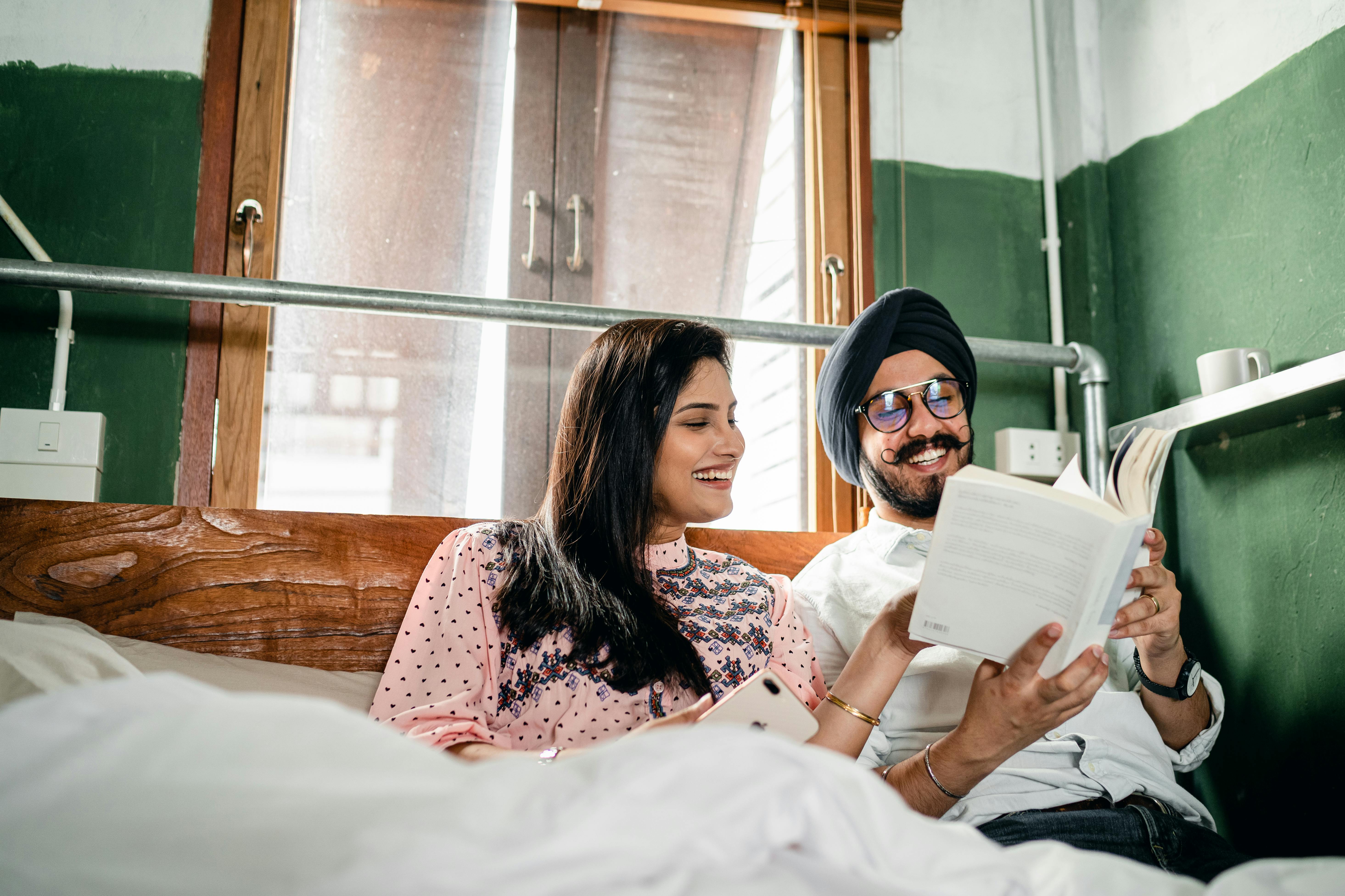 happy couple reading book and communicating cheerfully at home