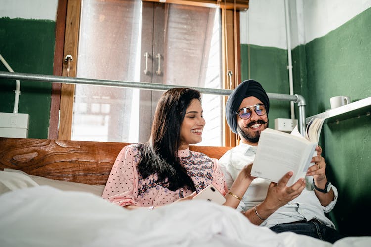 Happy Couple Reading Book And Communicating Cheerfully At Home