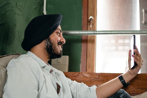 Young man in turban communicating via video call on mobile