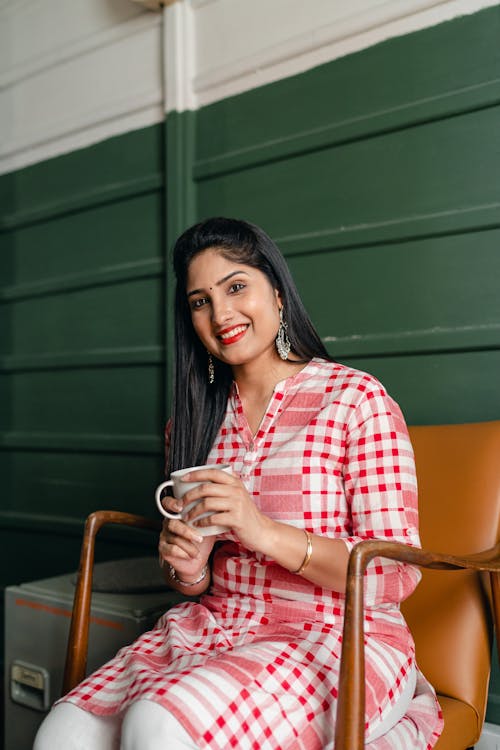 Smiling woman with cup of beverage on chair