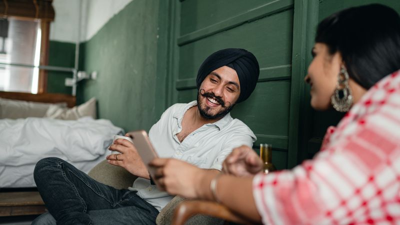 Indian couple laughing together while browsing sex toys for men on a phone