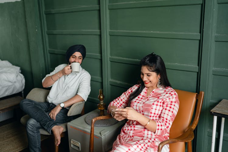 Young Indian Spouses Relaxing And Discussing Internet News At Home