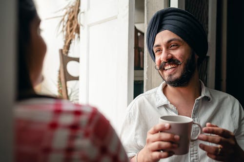 Cheerful man with coffee laughing together with woman