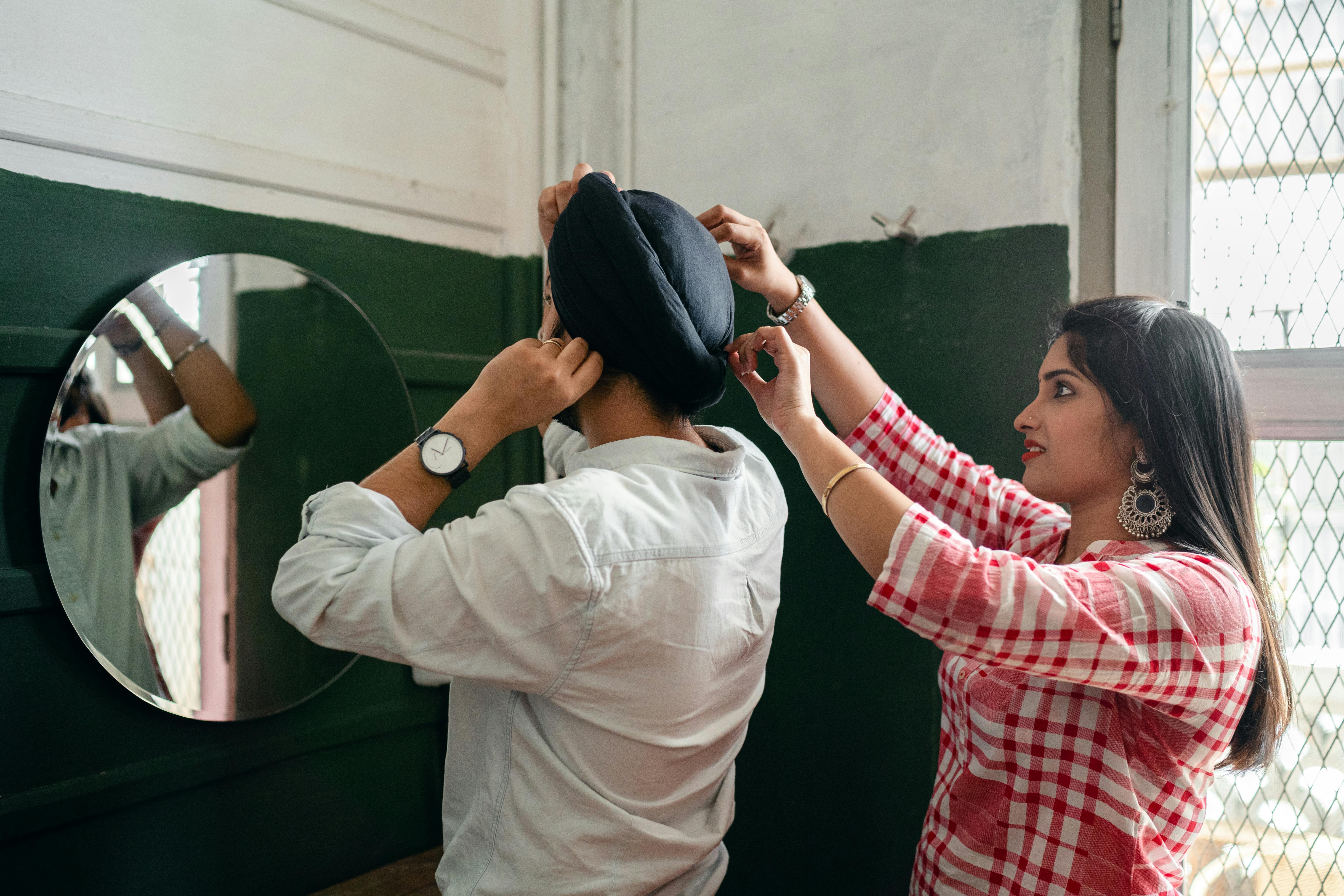 young indian woman helping husband with turban