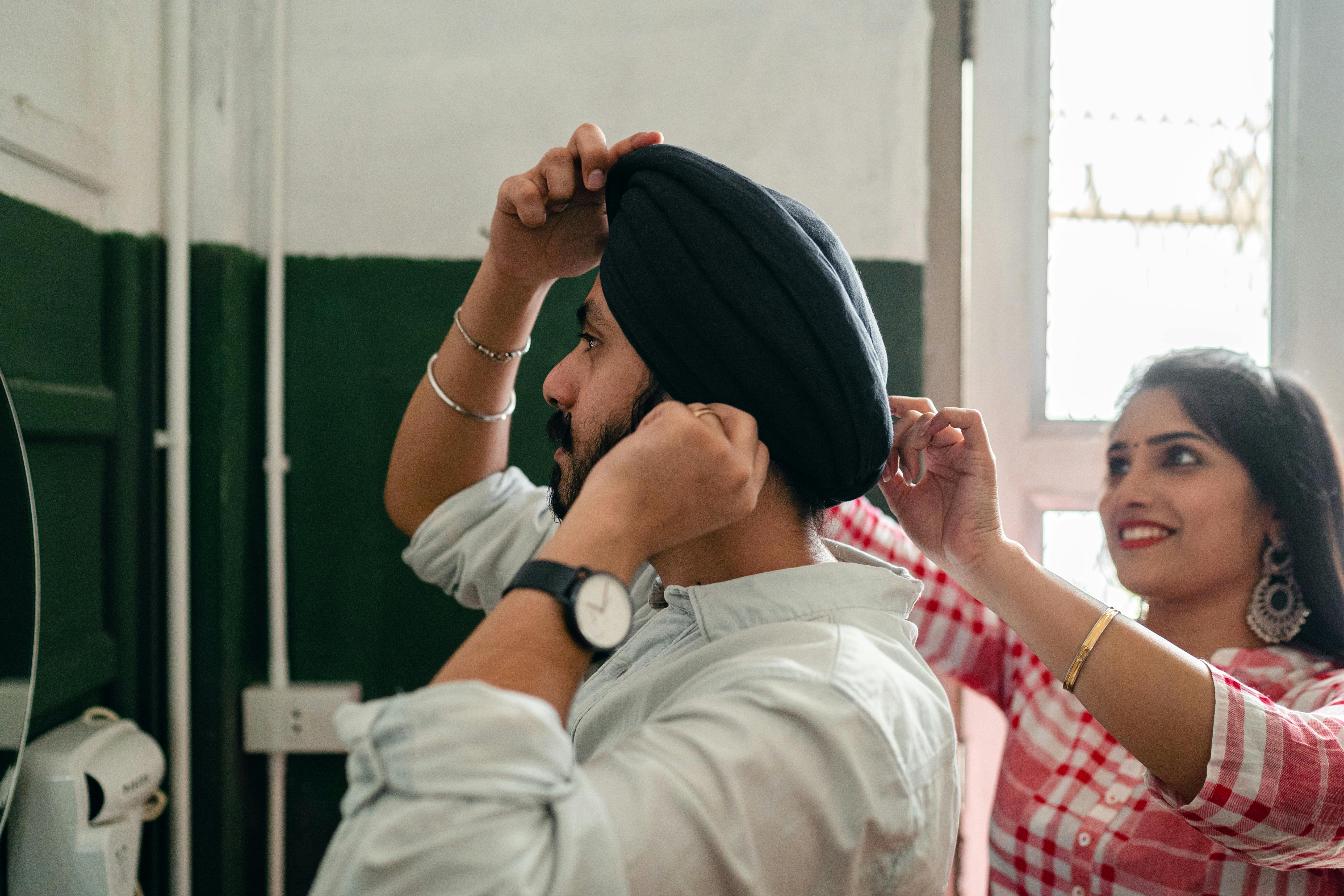 loving young wife helping bearded husband with traditional turban