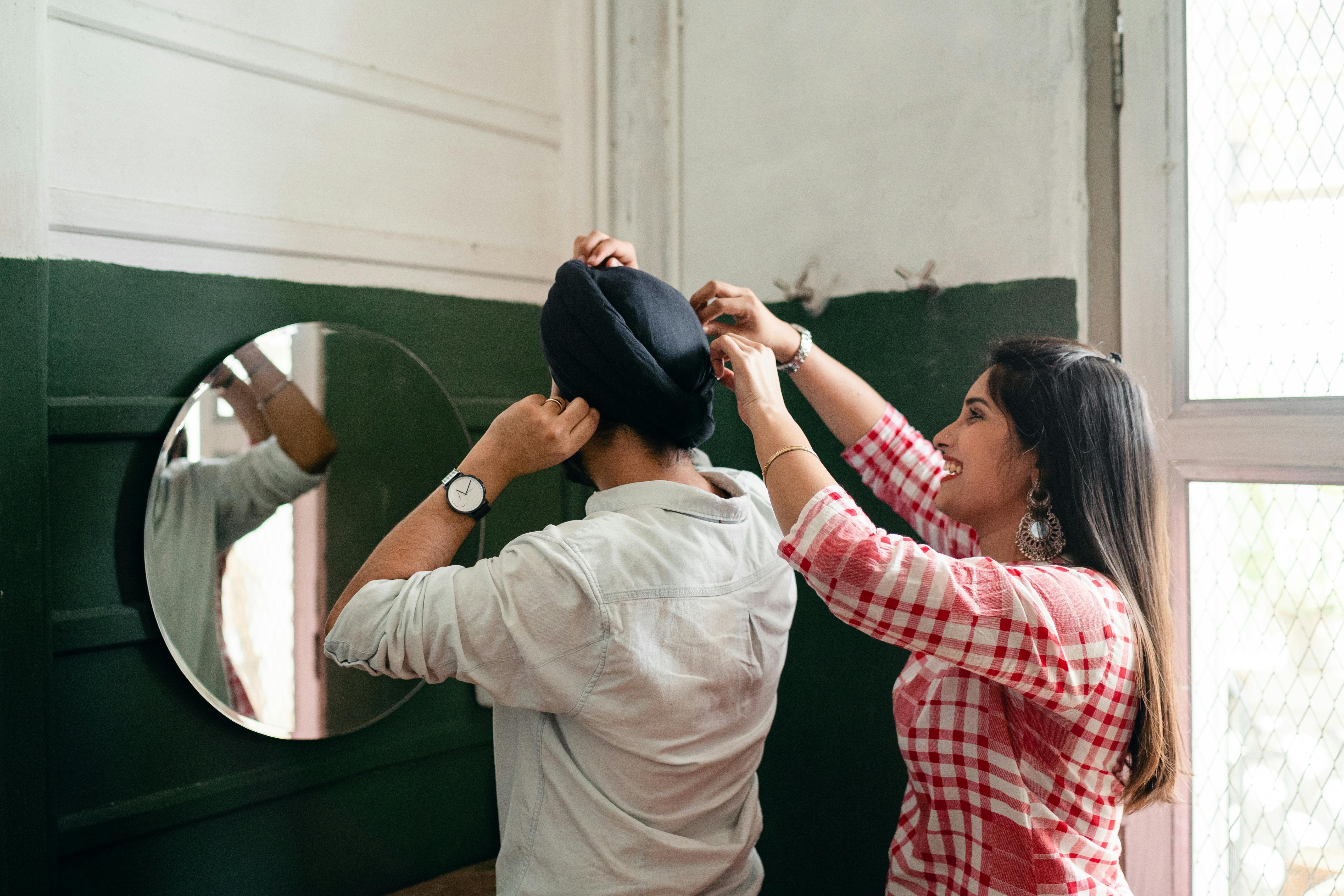 young indian woman assisting husband near mirror