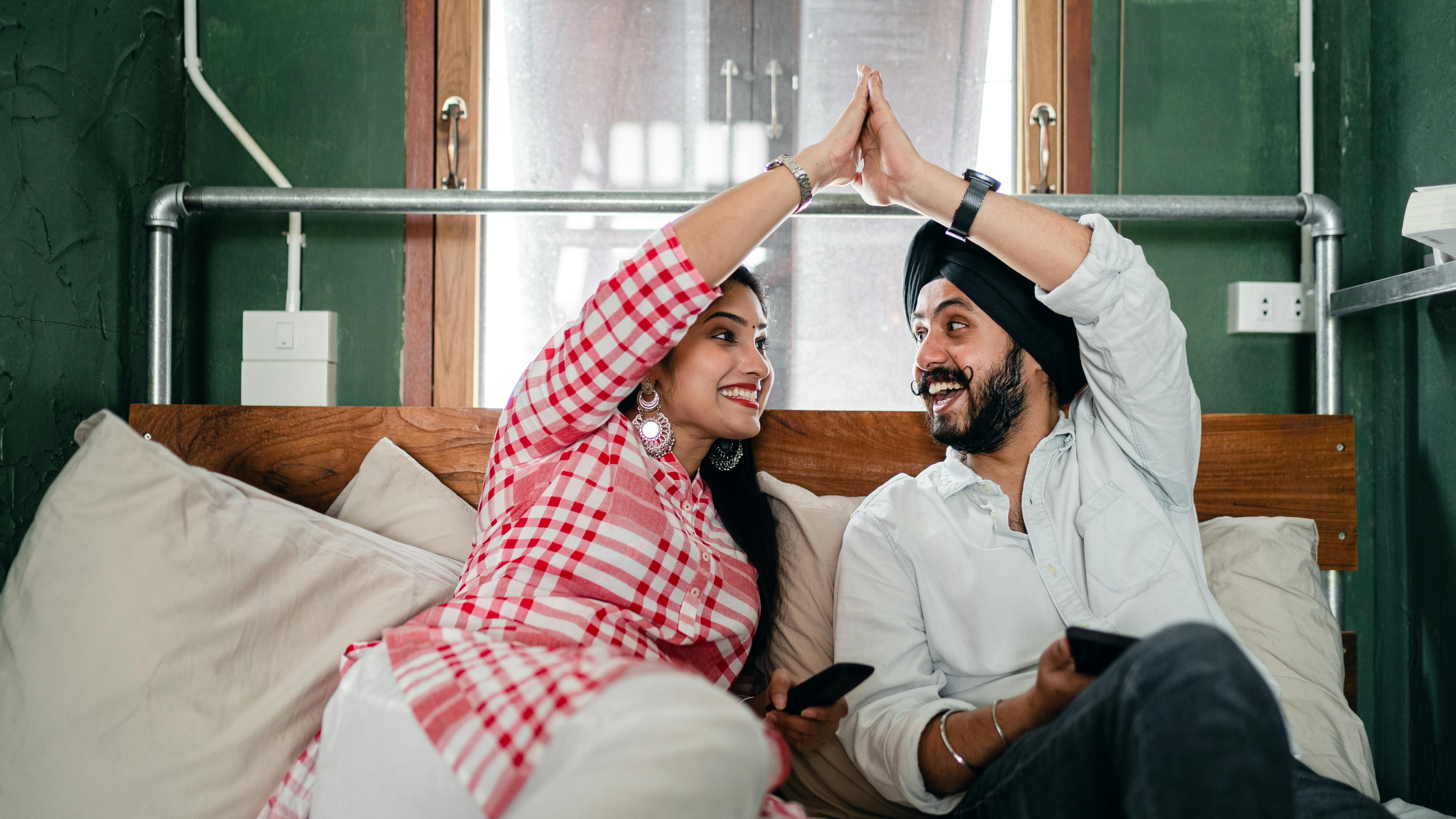 happy ethnic couple doing high five in living room