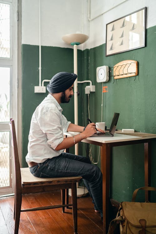 Young ethnic man using laptop in modern workplace