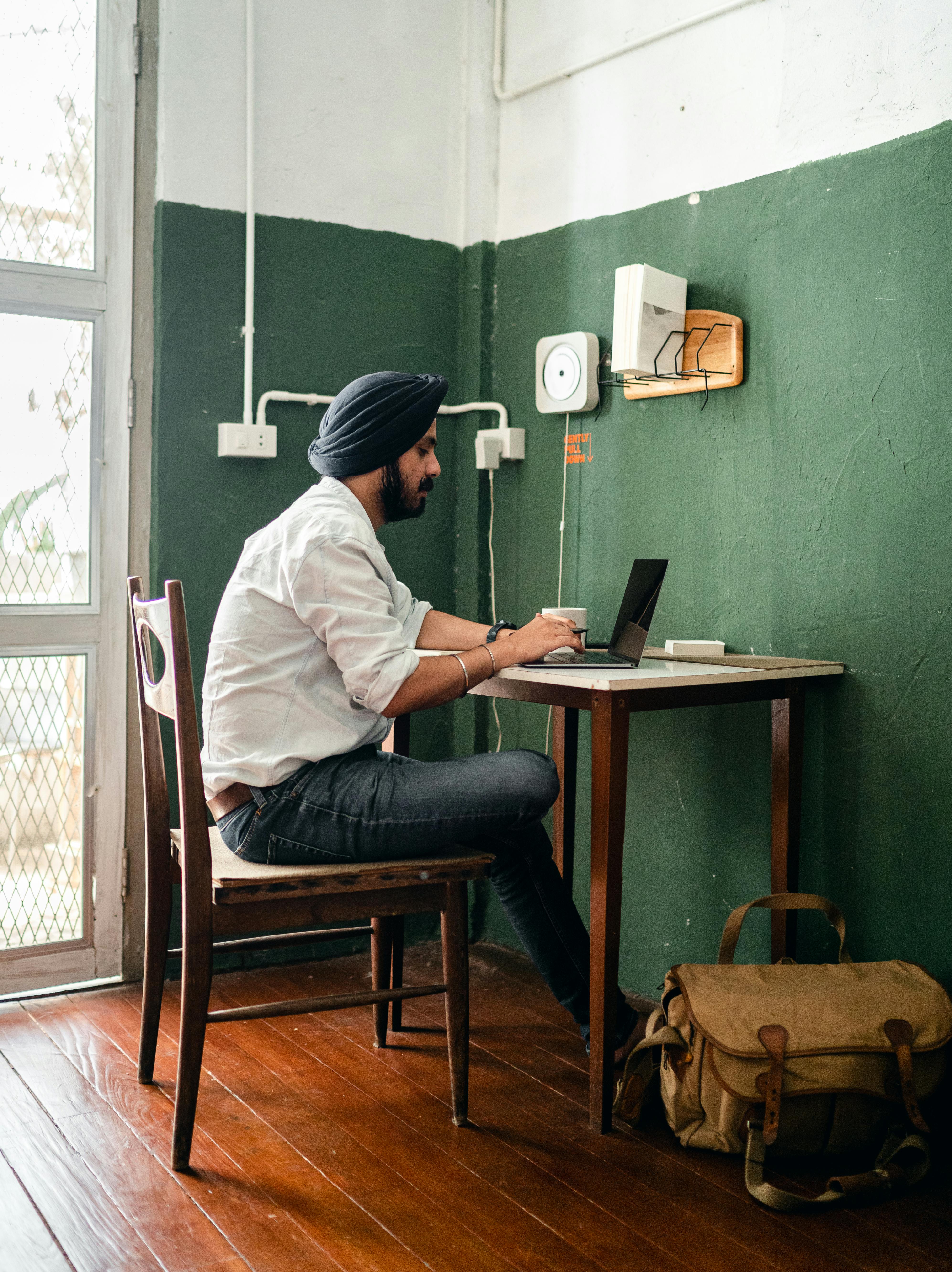 Focused young ethnic man browsing laptop at home