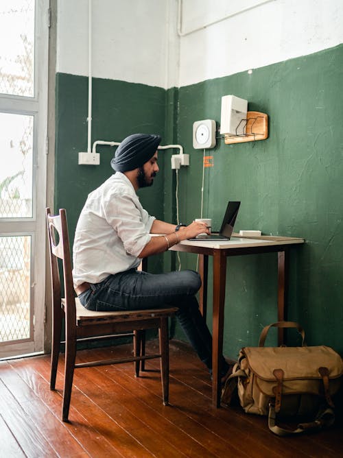 Free Focused young ethnic man browsing laptop at home Stock Photo