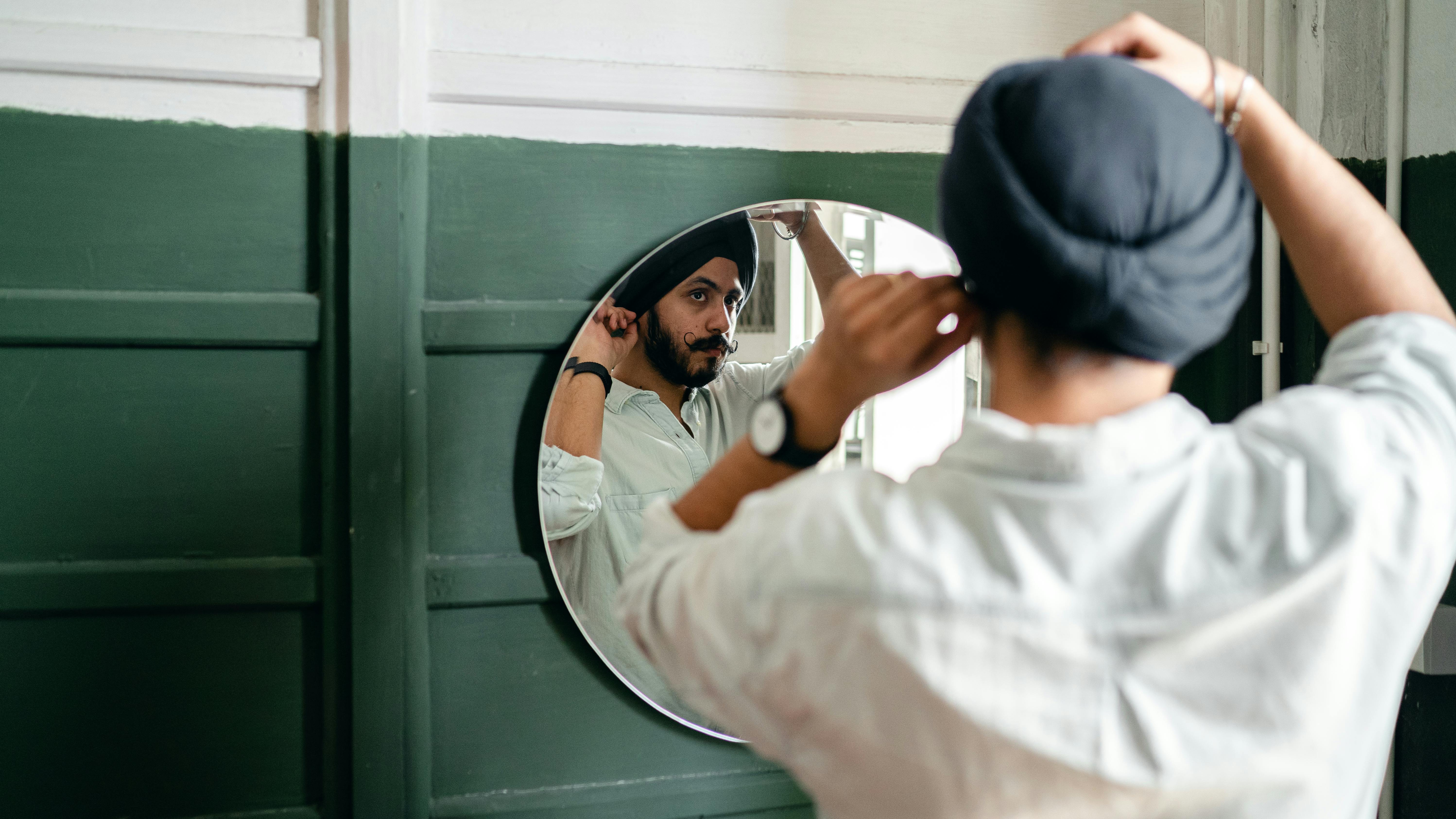 young ethnic man looking of mirror at home