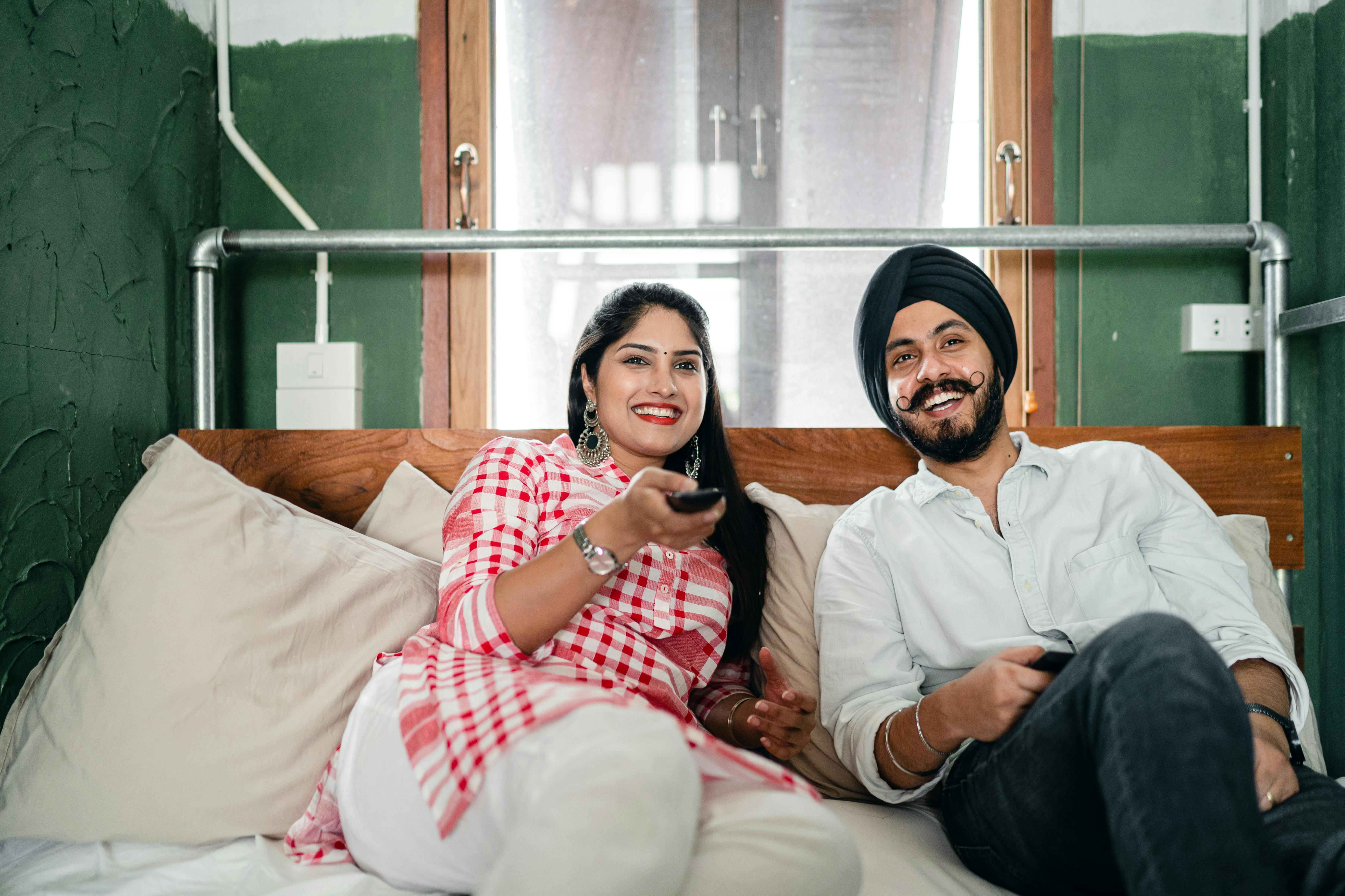 smiling ethnic couple using remote control in living room