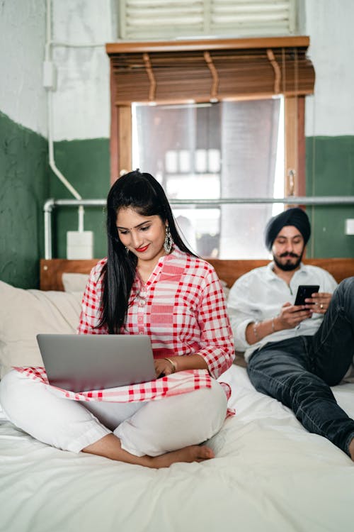 Young ethnic couple surfing internet in bedroom