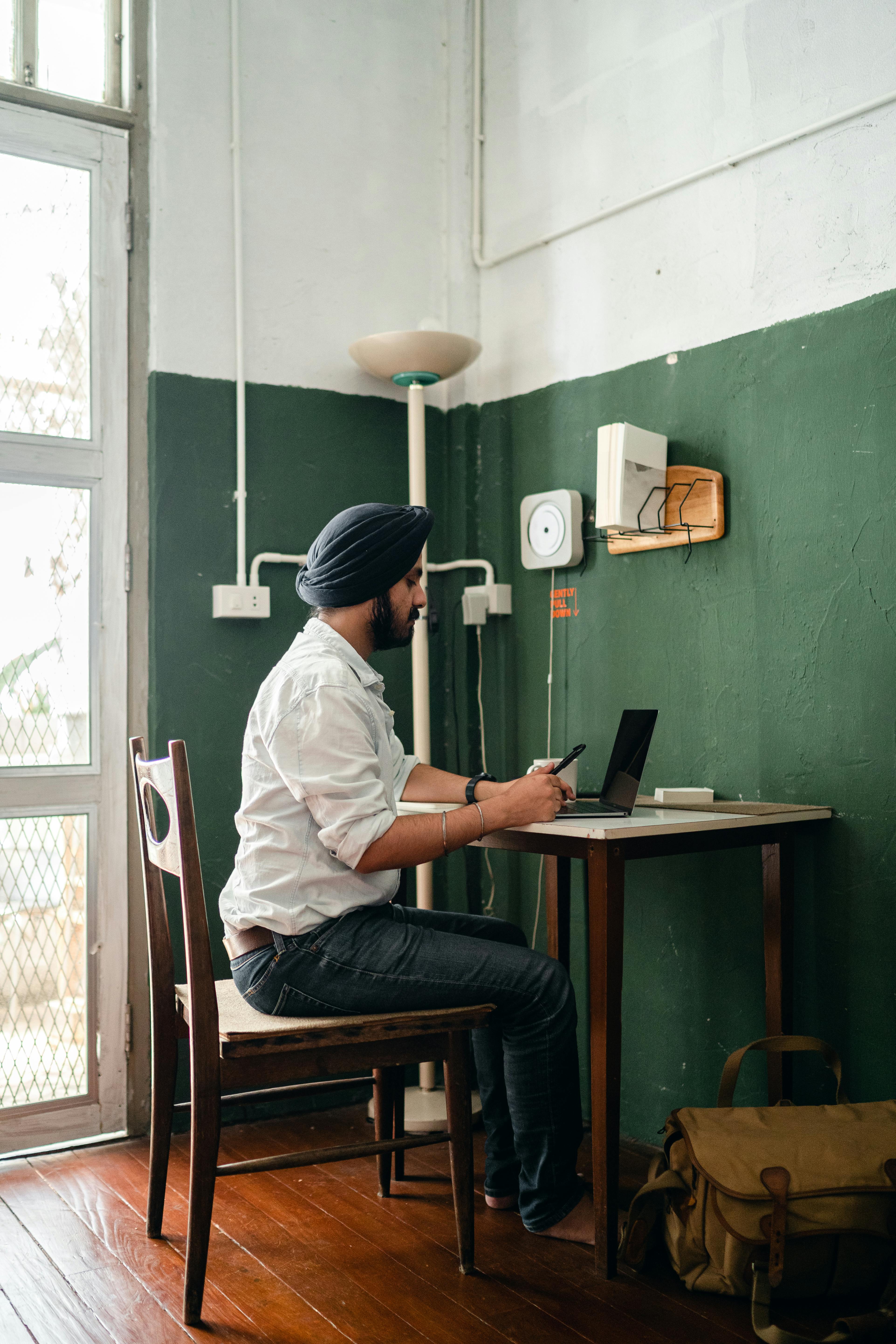 Serious ethnic man using smartphone in modern workplace