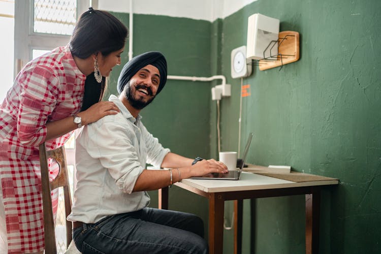 Ethnic Couple Laughing While Man Using Laptop