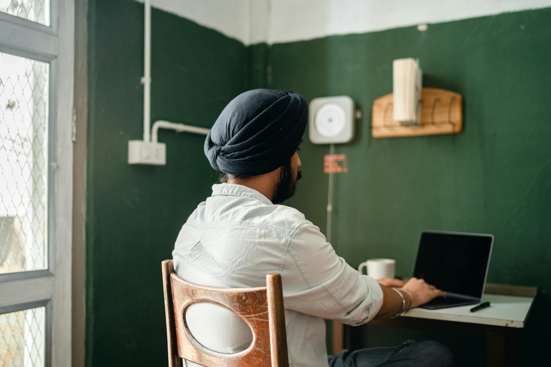 Unrecognizable Indian man using laptop while working at home