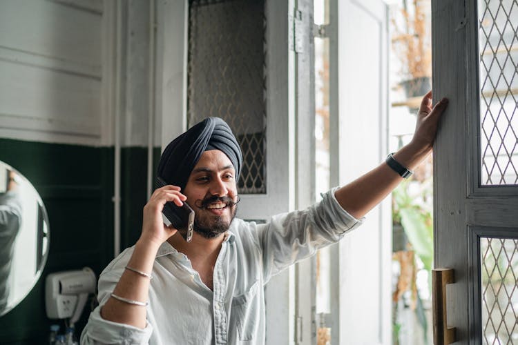 Young Smiling Sikh Man Speaking On Smartphone At Home