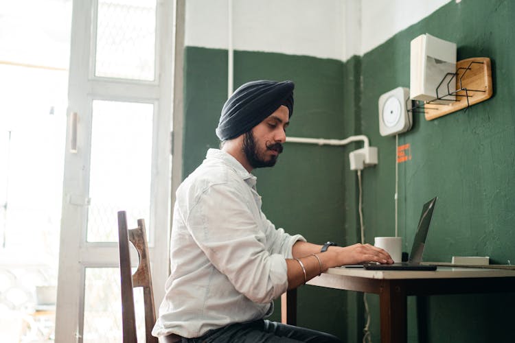 Concentrated Young Indian Businessman Working Remotely On Laptop