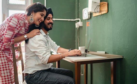 Joyful young couple using laptop at home, working together with smiles and affection.