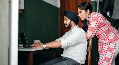 Focused young Indian couple browsing netbook at home