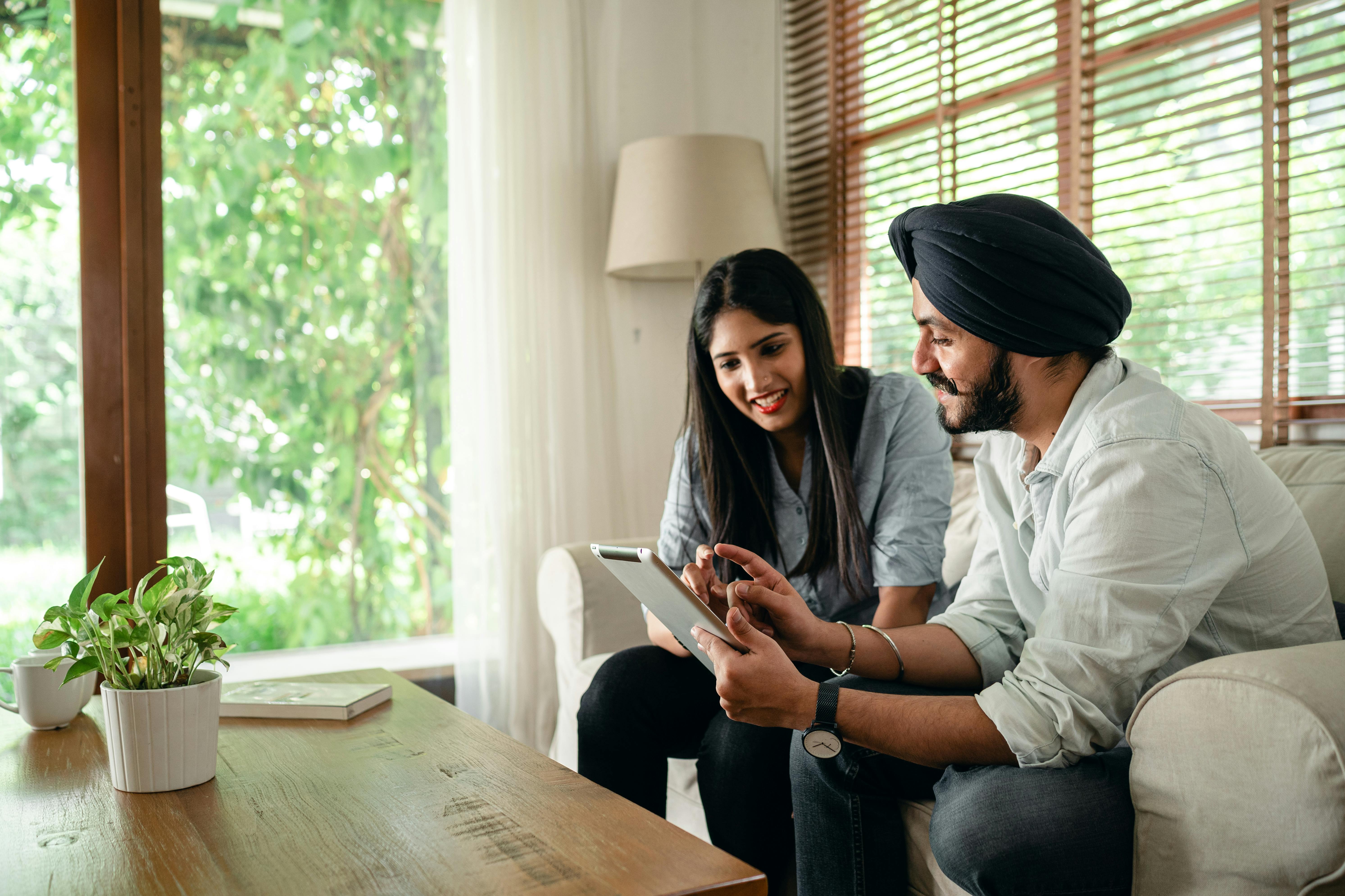 positive young indian colleagues using tablet in modern workspace