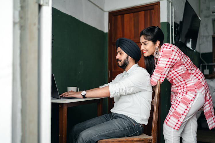 Young Indian Spouses Browsing Netbook During Online Work