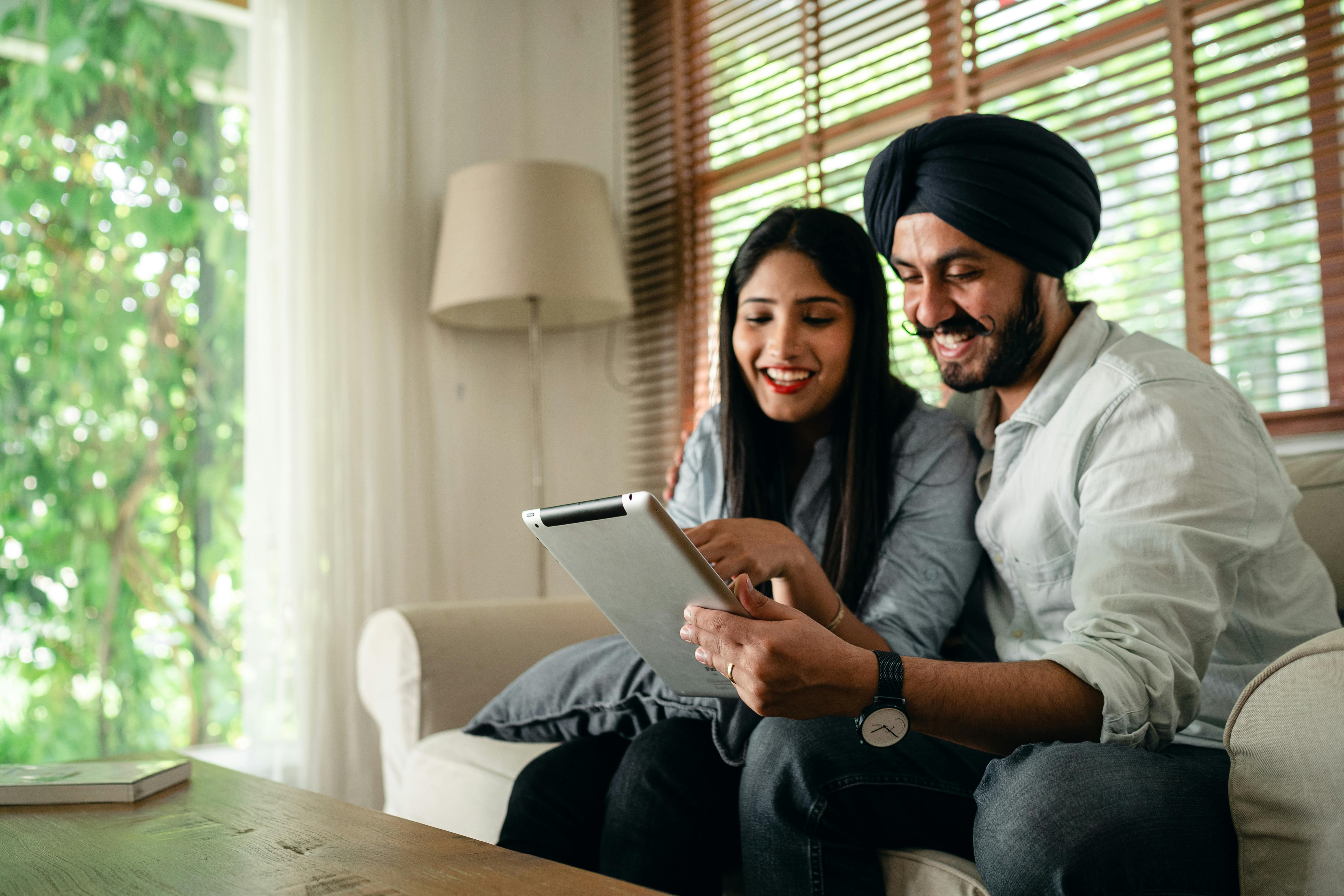 happy ethnic couple browsing tablet together