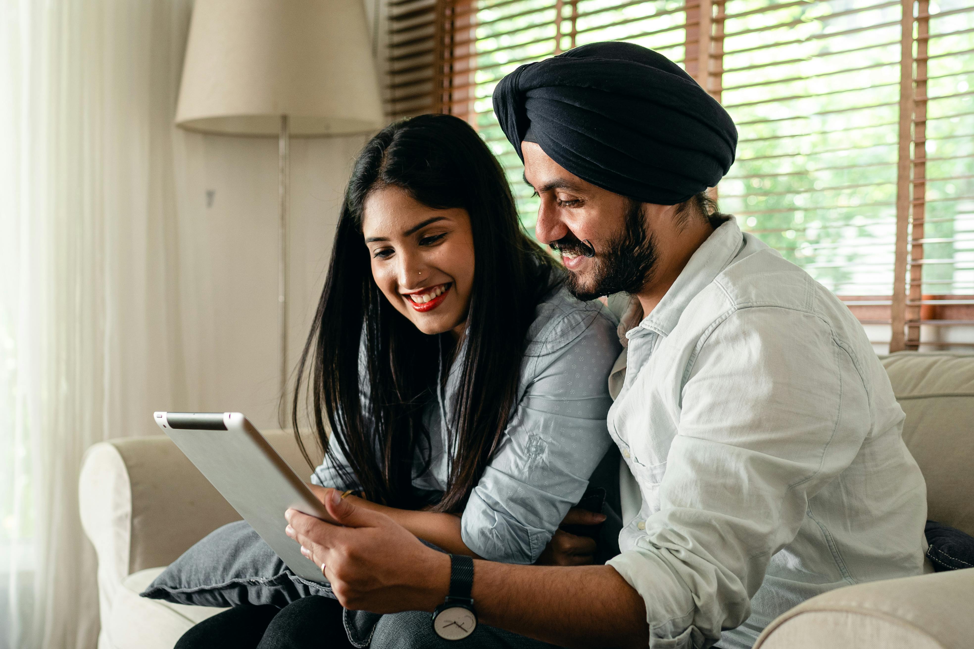 Calm ethnic couple browsing tablet and sitting in living room