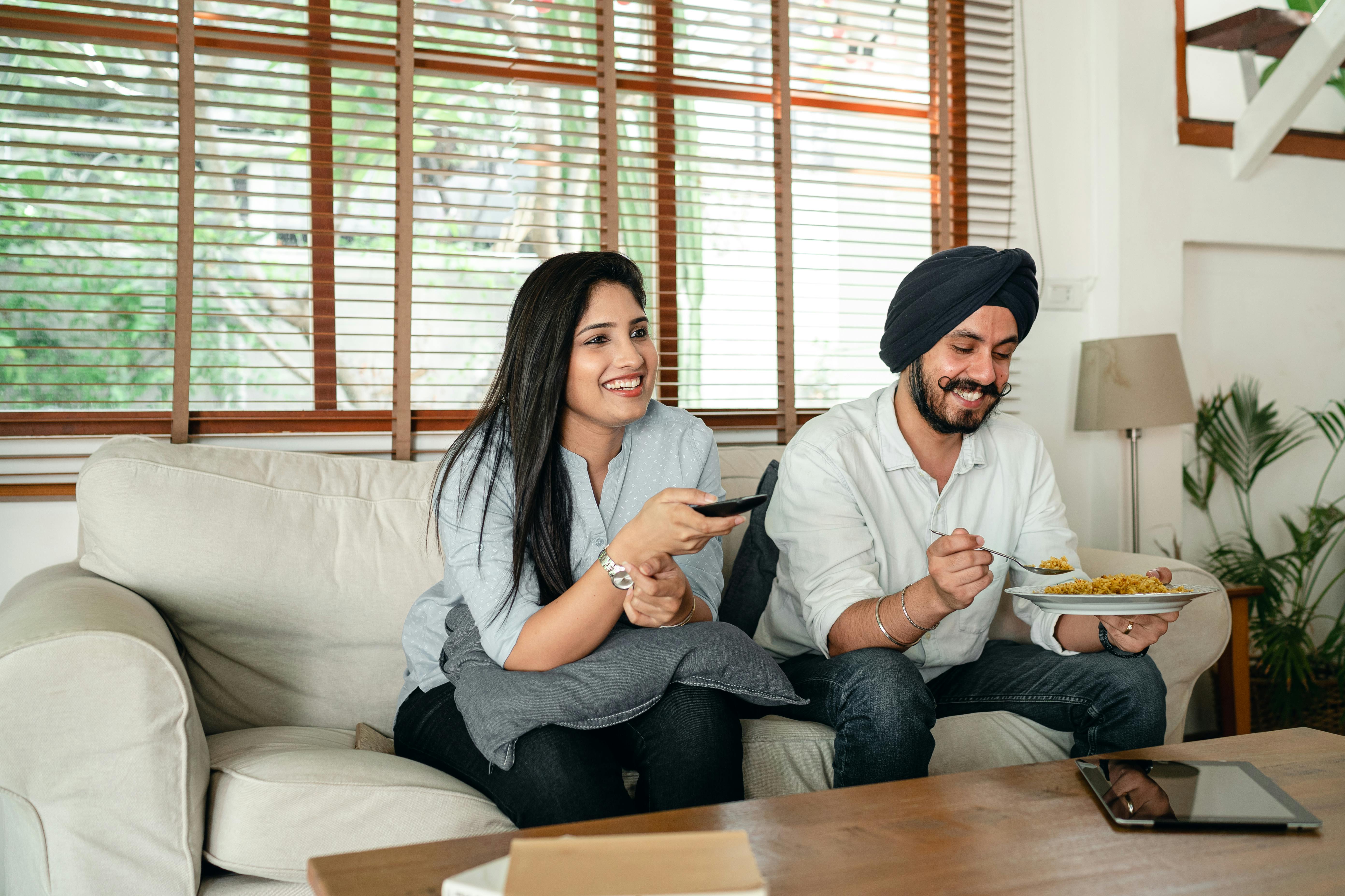 smiling couple watching tv together while sitting in living room