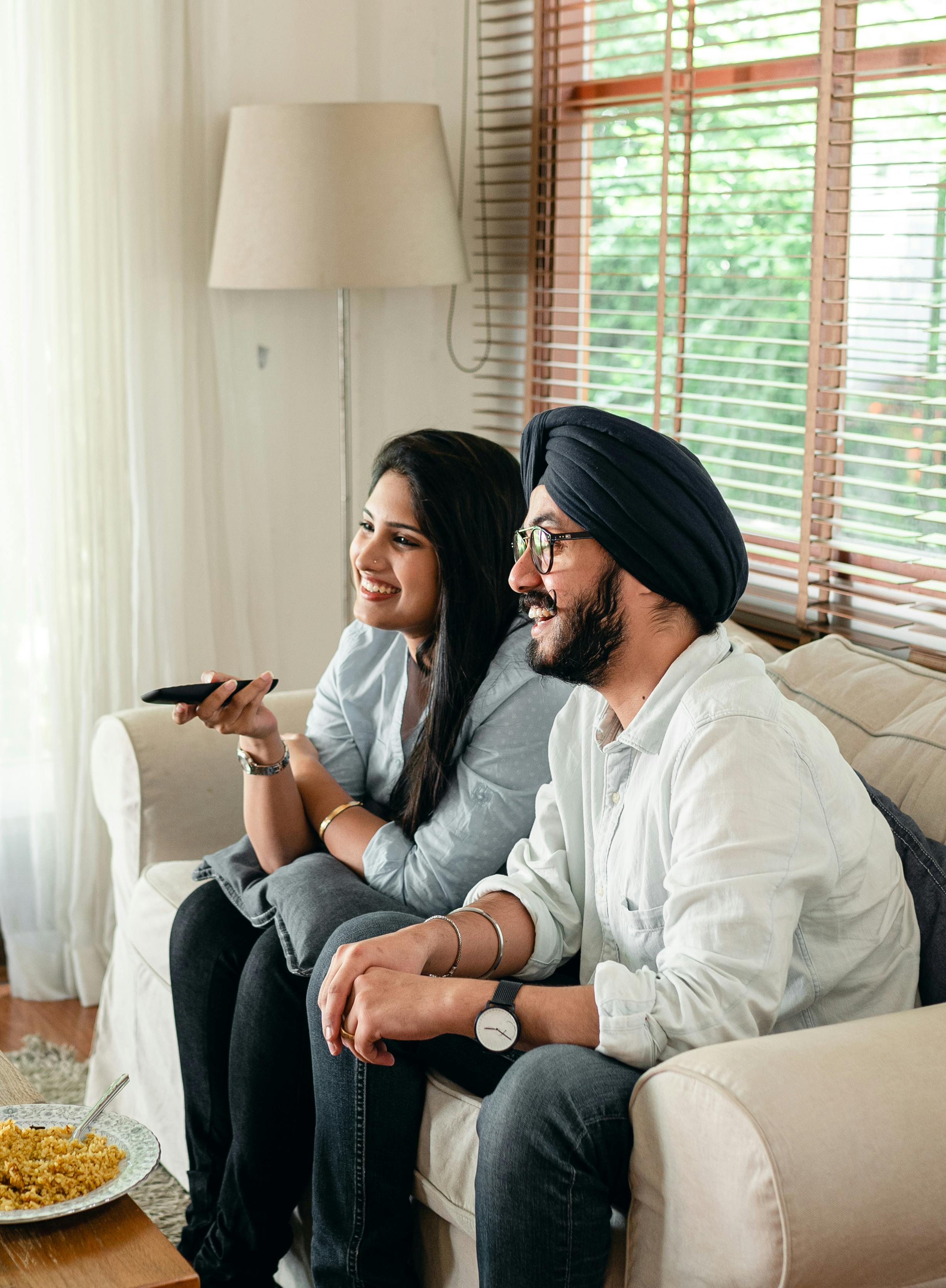 smiling couple watching tv while sitting on couch