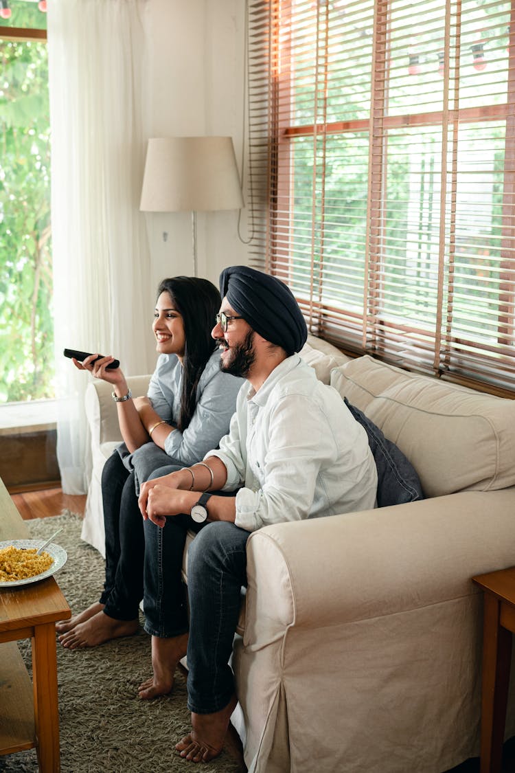 Cheerful Couple Sitting On Couch And Watching TV