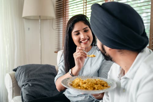 Smiling woman feeding man in turban
