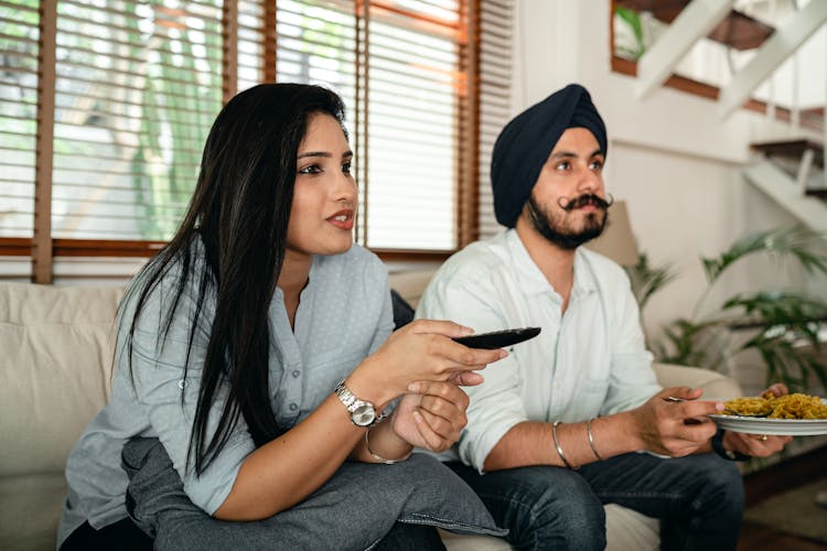 Serious Ethnic Couple Watching Movie On Sofa