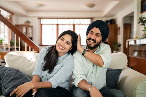 Playful Indian spouses having fun on sofa during weekend