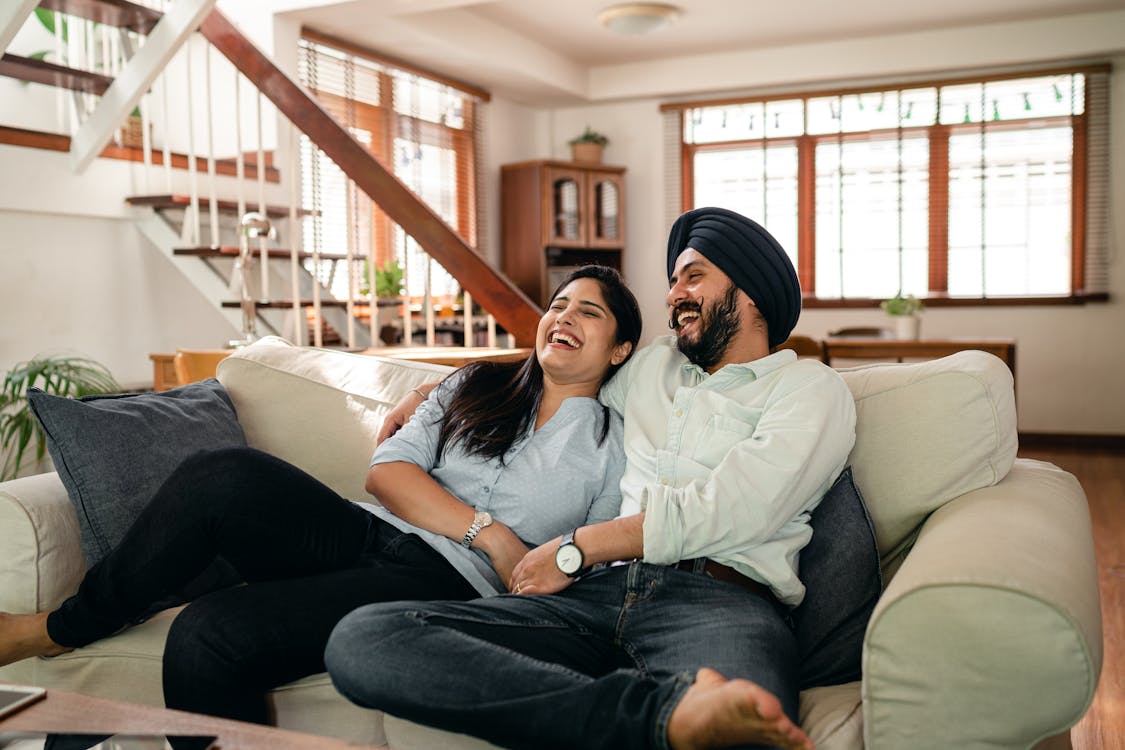 Laughing young Indian couple watching comedy movie together at home