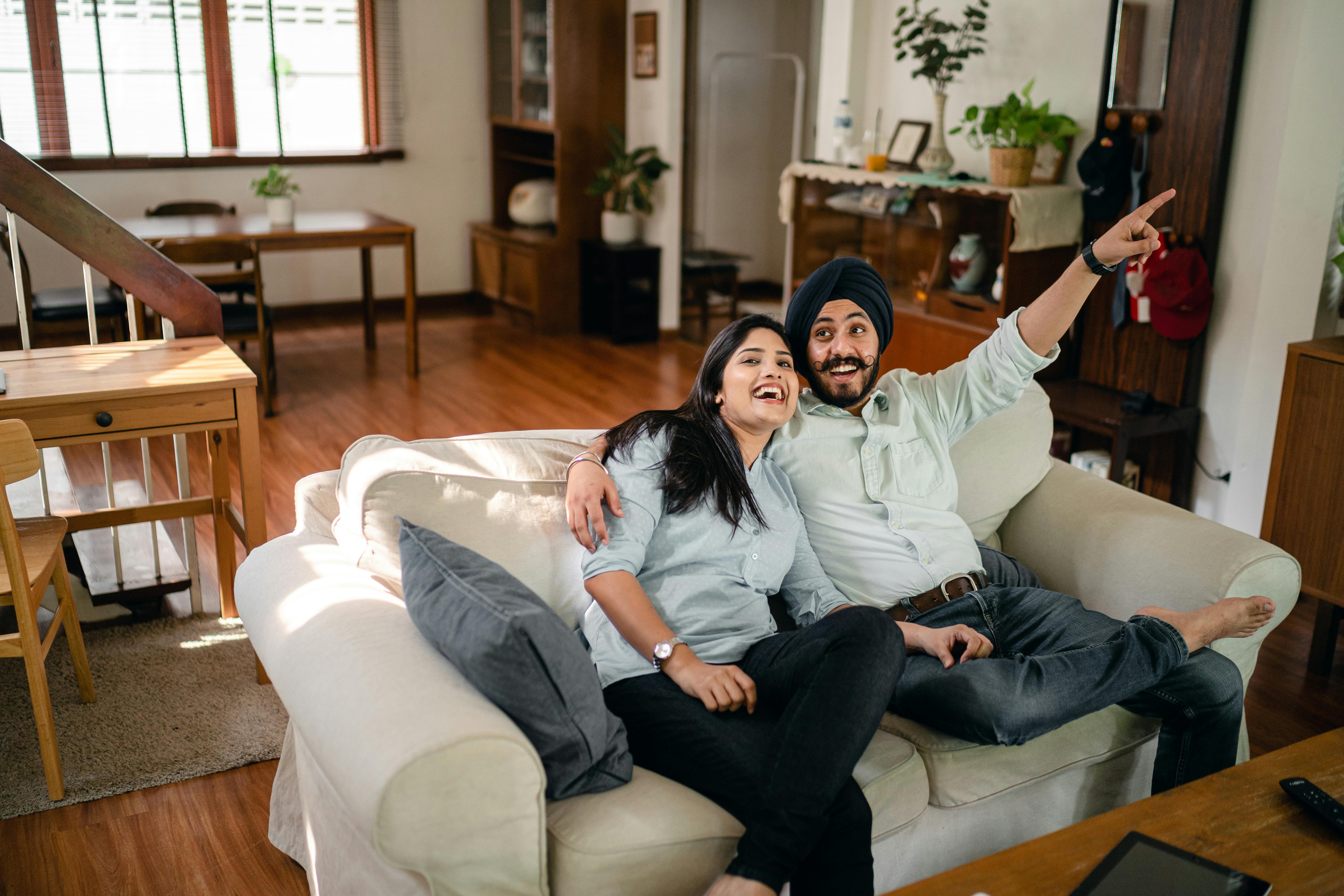 loving ethnic couple laughing on couch at home