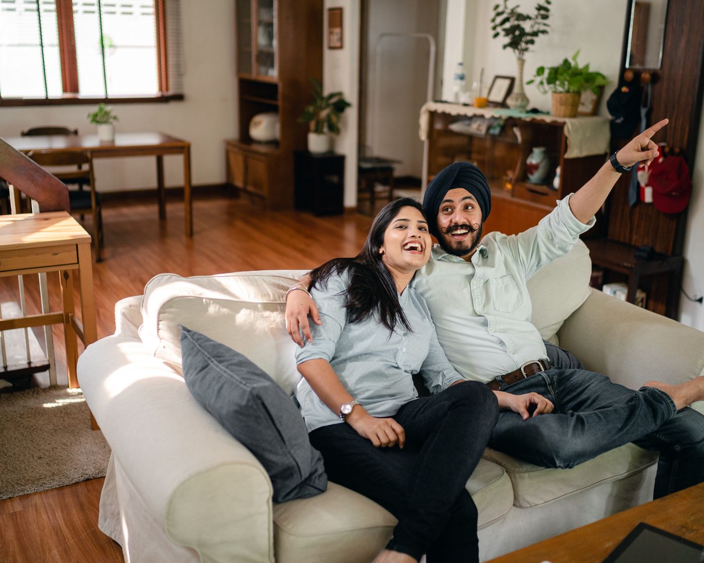 A couple laughing together on a sofa in a lived-in home