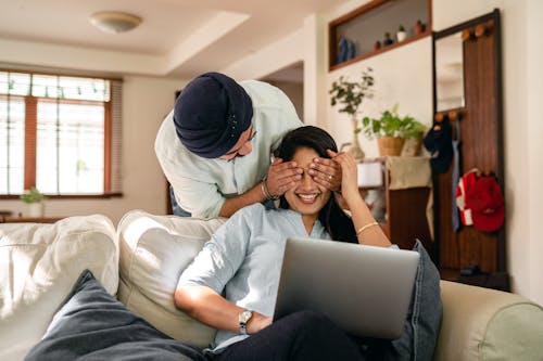 Cheerful ethnic couple with laptop at home