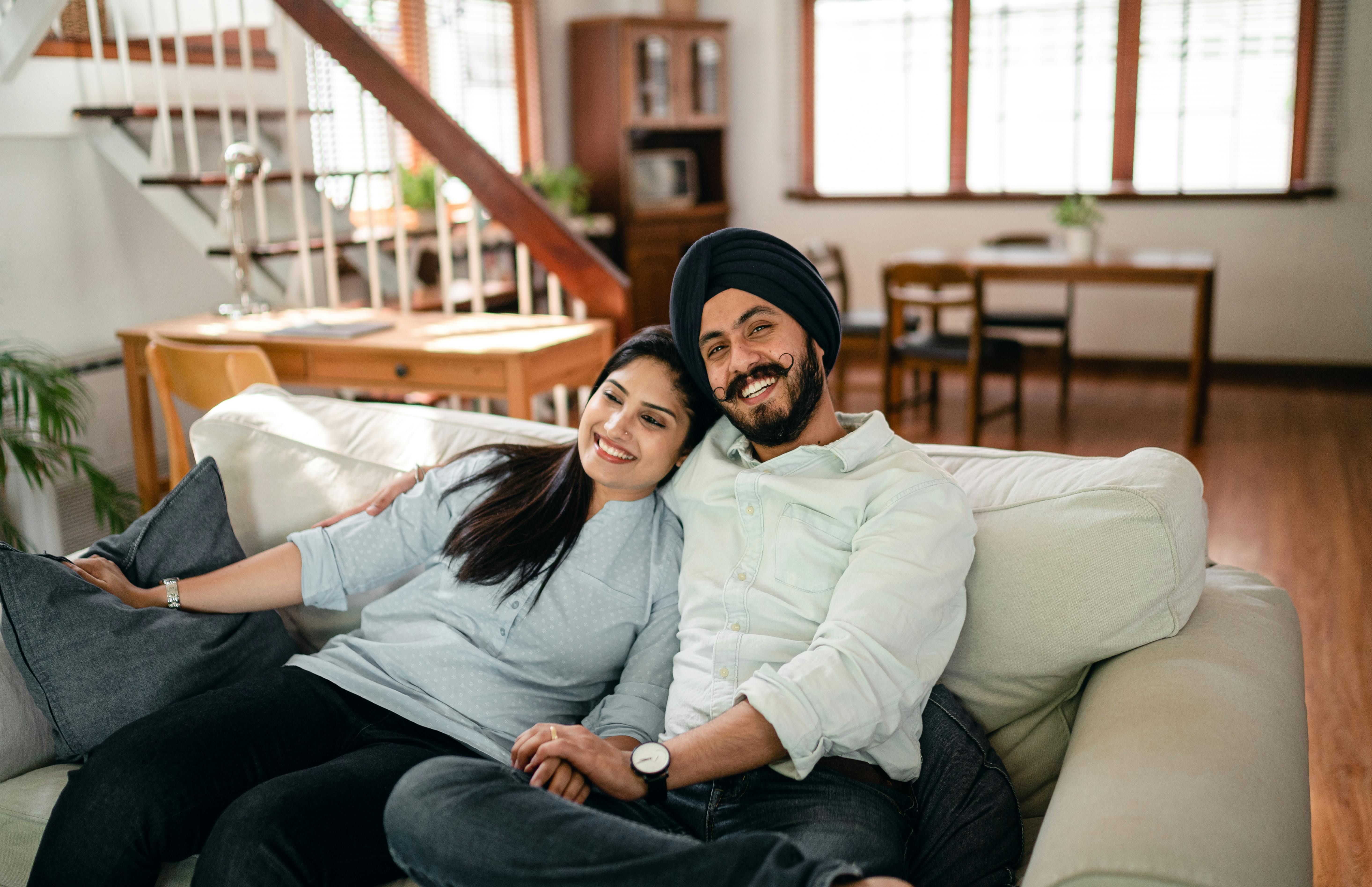 happy ethnic couple embracing on sofa at home