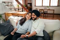 Positive ethnic couple resting on cozy couch in living room