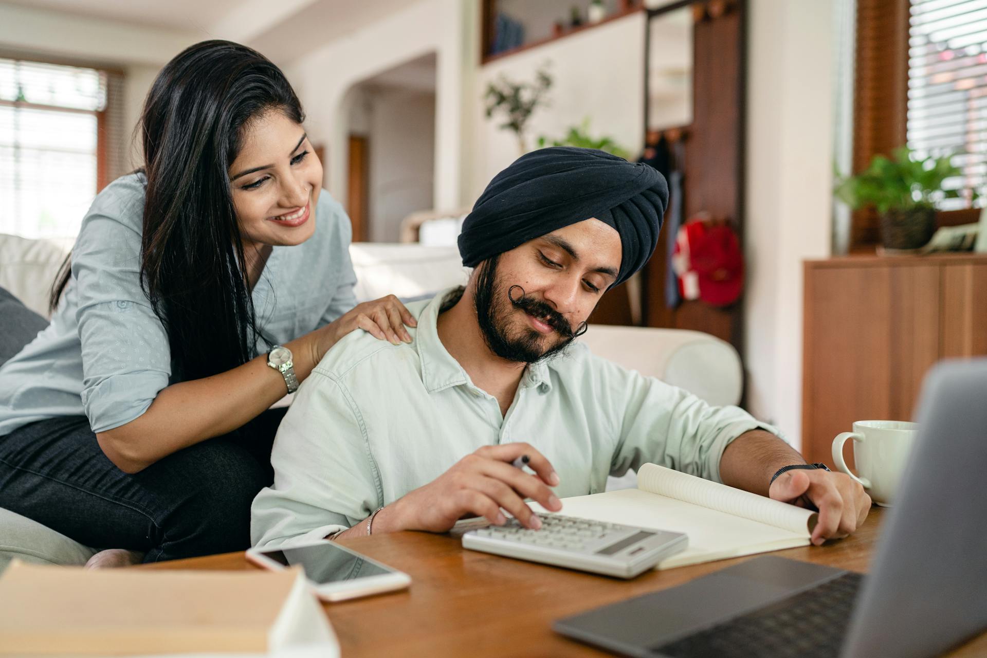 A happy Indian couple engaged in financial work together at home.