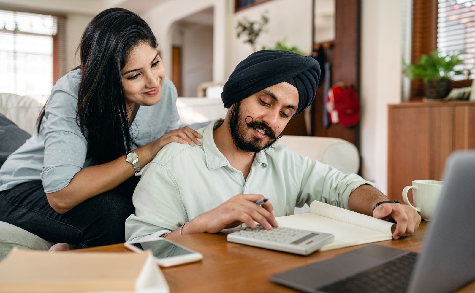 Asian couple na gumagamit ng calculator at notebook para gumawa ng financial plan