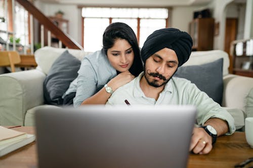 Happy ethnic couple using laptop at home