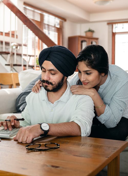 Free Focused young Indian couple working at home using calculator Stock Photo